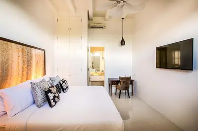 a bedroom with a white bed and a television at Villa Pulau Rumah in Seminyak