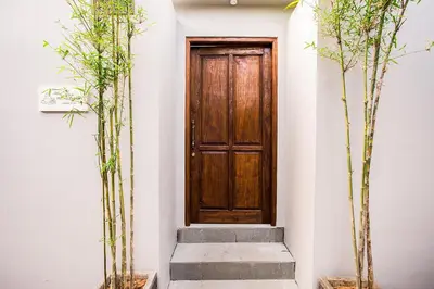 a wooden door in a white wall with two trees at Villa Pulau Rumah in Seminyak