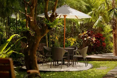 a table and chairs under an umbrella in a garden at Del Cielo Villa Jimbaran in Jimbaran