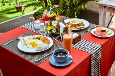 a table with breakfast foods and a cup of coffee at Palm Bamboo Hotel in Nusa Dua