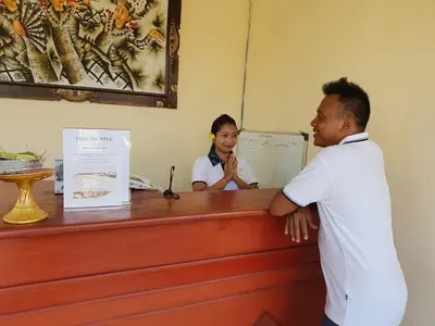 a man standing at a counter talking to a woman at Palm Bamboo Hotel in Nusa Dua