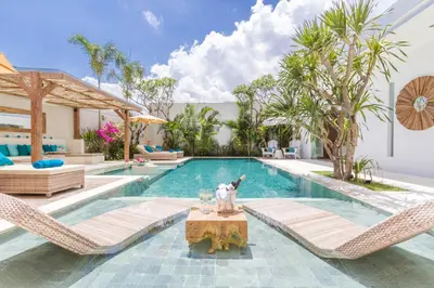 a swimming pool with chairs and a table in front of a house at Villa Smilla in Seminyak