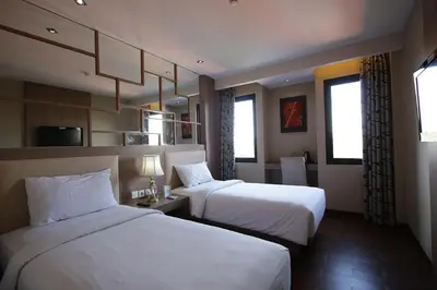 a hotel room with two beds and two windows at Serela Kuta in Kuta