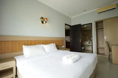 a bedroom with a white bed with a towel on it at Serela Kuta in Kuta