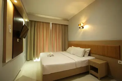 a hotel room with a bed and a television at Serela Kuta in Kuta