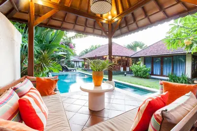 an outdoor patio with a couch and a pool at Villa Santi Seminyak in Seminyak
