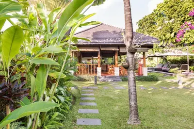 a garden with a pathway leading to a house at Villa Santi Seminyak in Seminyak