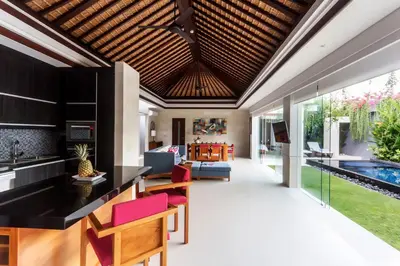 an open kitchen and living room with a ceiling at Villa by the Beach in Jimbaran