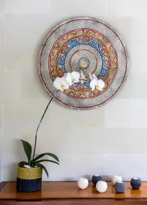 a plate on a wall with a plant on a shelf at Villa by the Beach in Jimbaran