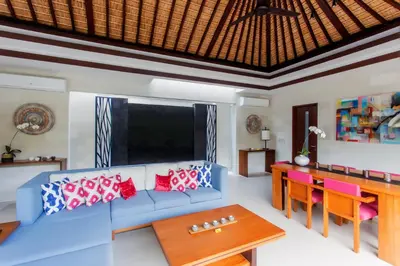 a living room with a blue couch and a table at Villa by the Beach in Jimbaran