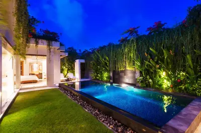 a swimming pool in the backyard of a house at night at Villa by the Beach in Jimbaran