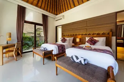 a bedroom with two beds and a desk and window at Adepa Resort in Canggu