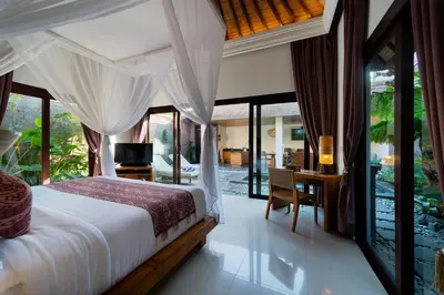 a bedroom with a bed and a desk and windows at Adepa Resort in Canggu