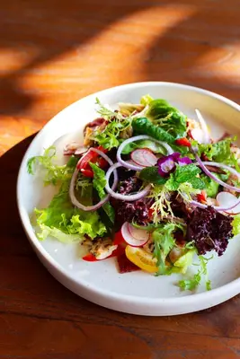 a salad on a white plate on a table at Adepa Resort in Canggu