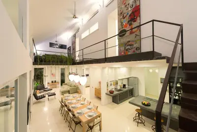 a living room with a dining table and a staircase at Villa Alina in Seminyak
