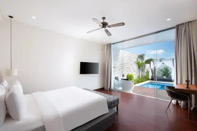 a white bedroom with a bed and a desk and a window at The Daha Luxury Villas in Seminyak