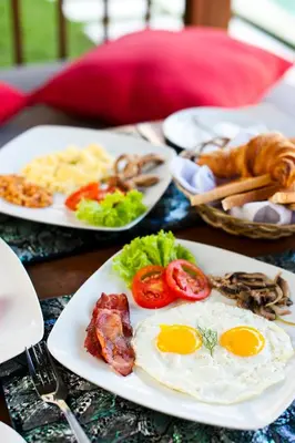 a table topped with plates of food with eggs and bacon at Villa Zanissa in Seminyak