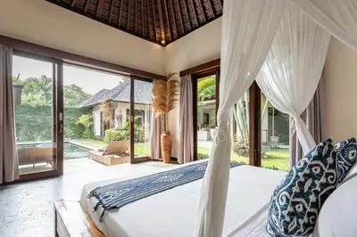 a bedroom with a bed and large windows at Villa Tiga Mangga by Optimum Bali Villas in Seminyak