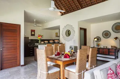 a dining room with a wooden table and chairs at Villa Tiga Mangga by Optimum Bali Villas in Seminyak