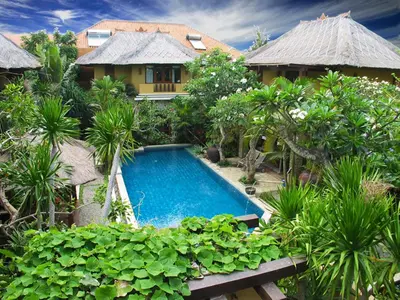 a villa with a swimming pool in front of a house at D'Sriwing Villa Gallery in Kuta
