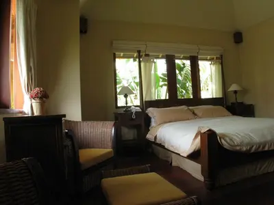 a bedroom with a bed and a window and a chair at D'Sriwing Villa Gallery in Kuta