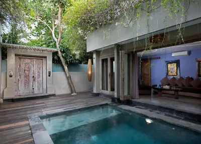 a house with a swimming pool next to a wooden deck at Blue Karma Dijiwa Seminyak in Seminyak