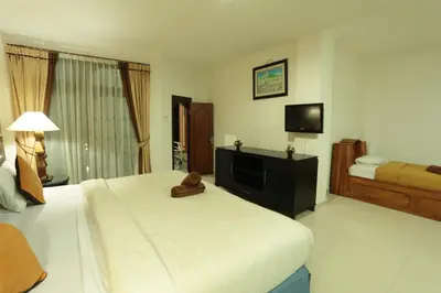 a hotel room with a bed and a flat screen tv at La Walon Hotel in Kuta