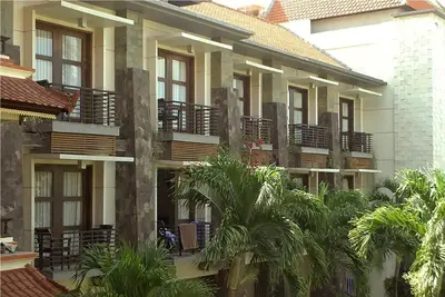 a building with palm trees in front of it at La Walon Hotel in Kuta