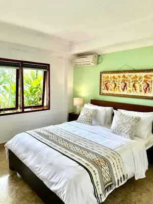 a bedroom with two beds and two windows at Ellies Hotel in Nusa Dua
