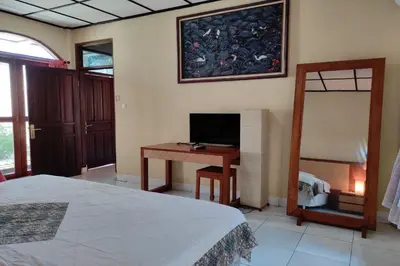 a bedroom with a bed and a desk with a television at Villa Puri Royan Jimbaran in Jimbaran