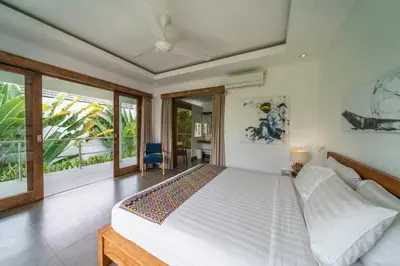 a bedroom with a large white bed and some windows at Villa Paloma - Chic Tropical Garden Villa with Outdoor Pool in Seminyak