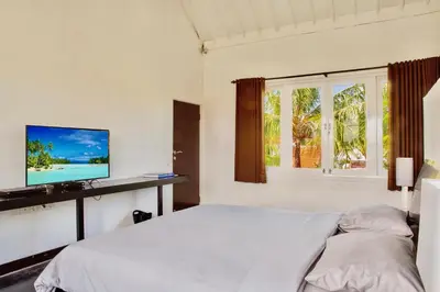 a white bedroom with a bed and a television at Villa JULIA | heart of Seminyak | 350m Beach in Seminyak