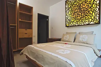 a bedroom with a bed with a painting on the wall at Villa Zaïna in Seminyak