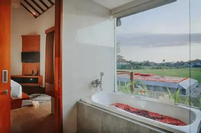 a bath tub in a room with a large window at The Wina Villa Seminyak by The Wina Resorts in Seminyak