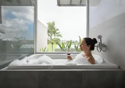 a woman sitting in a bath tub with a glass of wine at The Wina Villa Seminyak by The Wina Resorts in Seminyak