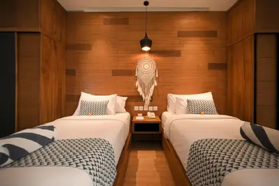 two beds in a room with wooden walls at The Wina Villa Seminyak by The Wina Resorts in Seminyak