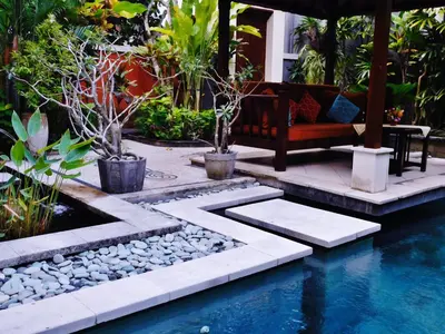 a garden with a bench and a swimming pool at Villa Kora in Seminyak