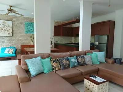 a living room with a brown couch and a kitchen at Villa Kora in Seminyak
