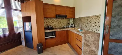 a small kitchen with wooden cabinets and a refrigerator at Sanur Seaview Hotel in Sanur