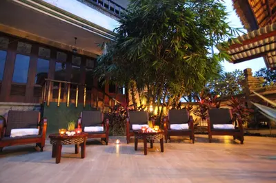 a patio with chairs and tables and a tree at Sanur Seaview Hotel in Sanur