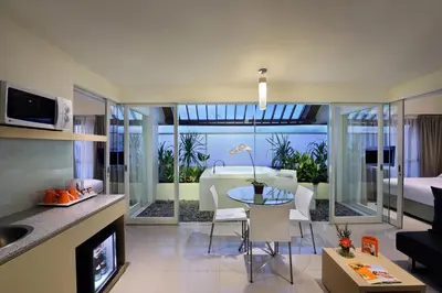 a kitchen and living room with a table and a living room at HARRIS Hotel & Residences Sunset Road in Kuta
