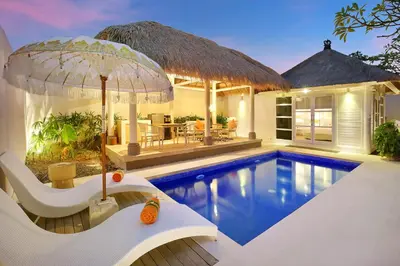 a villa with a swimming pool and a house at HARRIS Hotel & Residences Sunset Road in Kuta