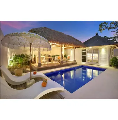 a villa with a swimming pool and a house at HARRIS Hotel & Residences Sunset Road in Kuta