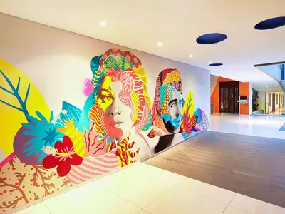 a room with a mural of three women on the wall at Primera Hotel Seminyak in Seminyak