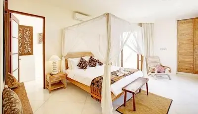 a bedroom with a canopy bed and a chair at Villa Sahaja in Canggu