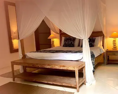 a bedroom with a canopy bed and a wooden bench at Villa Sahaja in Canggu