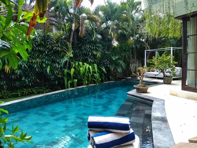 a swimming pool with two pillows in a garden at Villa Sahaja in Canggu