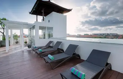 a room with chairs and a balcony with a view at Kuta Beach Hotel in Kuta