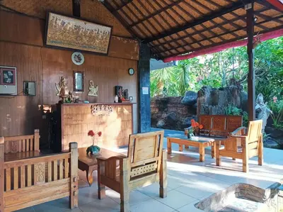 a patio with wooden chairs and a table at Sapta Petala Hotel in Kuta