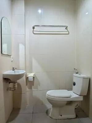 a white bathroom with a toilet and a sink at Sapta Petala Hotel in Kuta